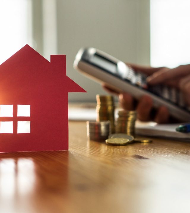 Buying and selling houses and real estate prices concept. Man using calculator to count rent, money or home insurance cost. Calculating mortgage, loan or investment.